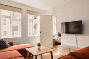 ein Wohnzimmer mit einem Sofa und einem Fernseher an der Wand in der Unterkunft Leiligheter i sentralt Bergenshus in Bergen