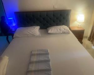 キガリにあるALEX's HOMEのヘッドボードと枕が2つ付いた大きな白いベッド