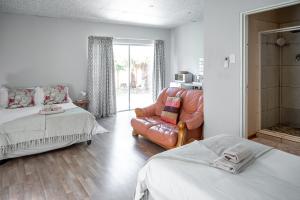 a bedroom with two beds and a leather chair at The Palms Guest House in Hopetown