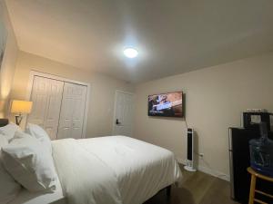 a bedroom with a white bed and a tv on the wall at Lumi Deluxe in Saskatoon
