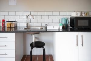 a kitchen counter with a sink and a stool at The Palms Guest House in Hopetown