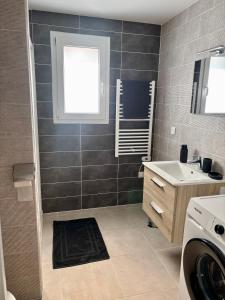 Un baño con lavabo y lavadora. en Maison individuelle meublée, en Chaignay