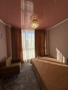 a bedroom with a bed and a chandelier and a chair at Розенталька in Mizikevycha