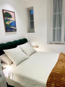 a white bed with white pillows in a bedroom at Apparemment cosy avec balcon plein centre de Cannes - Carla home in Cannes