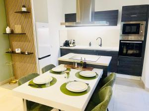 a kitchen with a white table with green chairs at Apparemment cosy avec balcon plein centre de Cannes - Carla home in Cannes