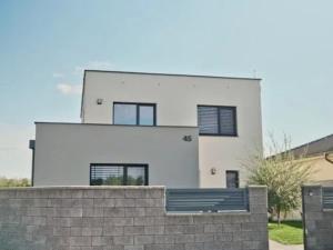 a white house behind a brick retaining wall at Exkluzívny rodinný dom Trnava - rodiny, pracovné cesty in Trnava