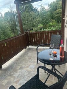 a patio with a table and two chairs and a glass of wine at Levendula Kuckó - PatakLak Vendégház in Orfű +1 photo