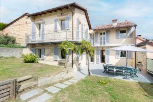 una casa con mesa y sombrilla en Cozy Court - Relax in Monferrato, en Grazzano Badoglio