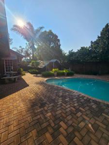 a backyard with a swimming pool and a palm tree at ZUCH Accommodation at Pafuri Self Catering - Guest Apartment in Polokwane