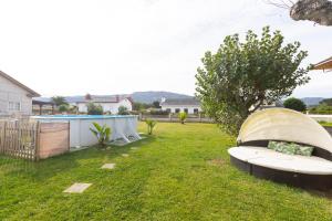 un patio trasero con un banco en el césped en Villa Las Catedrales - Frente a la playa - Amplio jardín - Piscina, en Barreiros