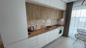 eine Küche mit weißen Schränken und einem Waschbecken in der Unterkunft Velora Apartments in Năvodari