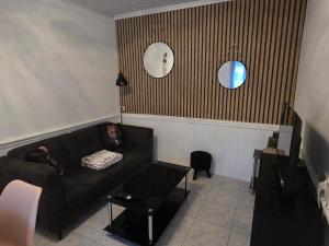 a living room with a black couch and two mirrors at Maison du bonheur in Montier-en-Der