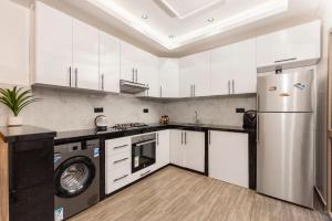 una cucina con mobili bianchi e un frigorifero di Maryam hospitality tamraght beach apartment ad Agadir
