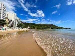 a sandy beach with buildings and the ocean at Apto 3 Quartos com Suíte e 3 Banheiros em Guarapari in Guarapari