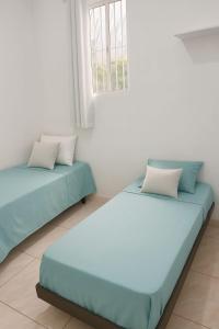 two beds sitting in a room with a window at Doce Lar 58 - Quarto Compartilhado in Cabo de Santo Agostinho