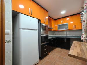 a kitchen with orange cabinets and a white refrigerator at Amplio adosado en Atarfe in Atarfe