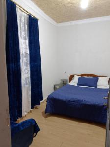 a bedroom with a blue bed and blue curtains at Sweetnight apartments in Mestia