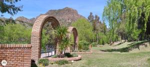a brick arch with two palm trees in a garden at VALLE GRANDE - CASA ARAUCARIA - SOLAR DEL VALLE in Valle Grande