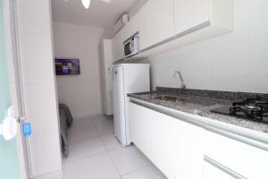 a white kitchen with a sink and a refrigerator at Loft Murano in Paulínia