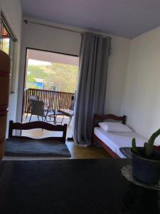 a bedroom with a bed and a view of a balcony at Hospedagem Olhos d'Água in Alto Paraíso de Goiás