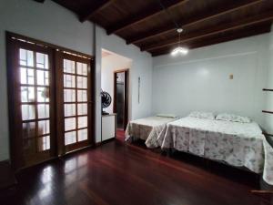 a bedroom with two beds in a room with wooden floors at Casa com suítes privativas - Localização no centro, perto de serviços e pontos turísticos in Belém