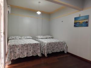 two beds in a room with white walls at Casa com suítes privativas - Localização no centro, perto de serviços e pontos turísticos in Belém +20 photos