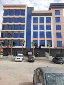 a large building with cars parked in a parking lot at شقق النخيل المخدومة in Al Kharj