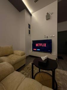 a living room with a tv and a couch and a table at شقق النخيل المخدومة in Al Kharj