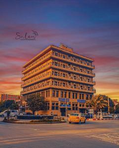 a large building with a car parked in front of it at Hotel El Emir Djelfa in Djelfa