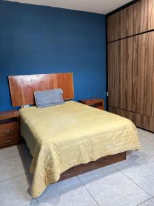 Un dormitorio con una cama con una pared azul. en Casa completa, en Mazatlán