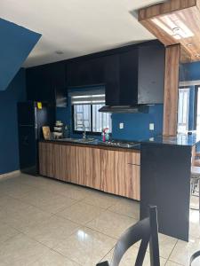 Una cocina con gabinetes de madera y un refrigerador negro. en Casa completa, en Mazatlán