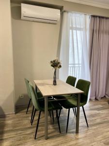 une table à manger avec des chaises vertes et un vase avec des fleurs dans l'établissement Sweet Apartment For Daily Rent, à Tbilissi 10 autres photos