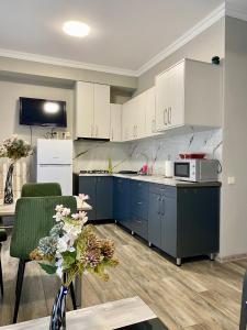 une cuisine avec des armoires bleues et une table fleurie dans l'établissement Sweet Apartment For Daily Rent, à Tbilissi