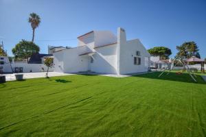 a white house with a large grass yard at Marisol Village in Corroios