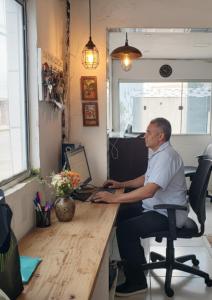 a man sitting at a desk with a computer at Refugio Executivo Litoral in João Pessoa