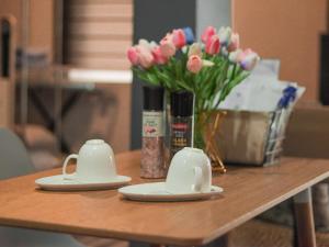 a table with two cups and a vase of flowers at Rvenue apartelle in Lucban