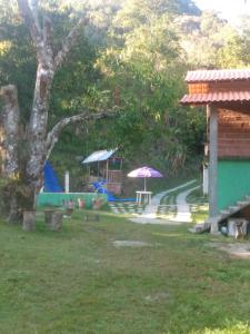 a yard with a house and a table and an umbrella at Villa Monteiro in Macaé