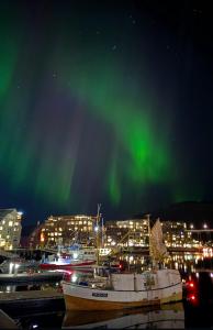 a group of boats docked under the northern lights at Stille leilighet med topp beliggenhet i Tromsø sentrum in Tromsø +6 photos