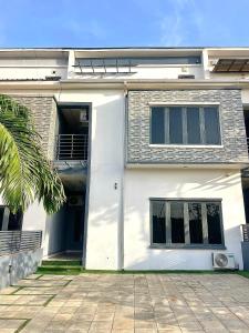 a white house with a palm tree in front of it at The Elegans Apartments in Rubuchi