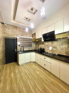 a kitchen with white cabinets and a wooden floor at The Elegans Apartments in Rubuchi +2 photos