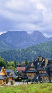 un groupe de maisons avec des montagnes en arrière-plan dans l'établissement Mio Apartament Z Ogródkiem Zakopane Kościelisko Free Parking, à Zakopane