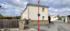 a white house with a stone wall next to a street at Le Petit Clazayéen in Bressuire