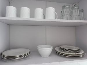 a white shelf with plates and cups and dishes at Apartament in Ploiești 6 in Ploieşti +2 photos
