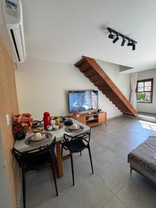 a living room with a table and chairs and a tv at Casa Duplex Praia da Bacutia Enseada Azul in Guarapari