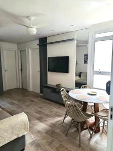un soggiorno con tavolo, sedie e televisione di Stay & Relax Enseada - Guarujá a Guarujá