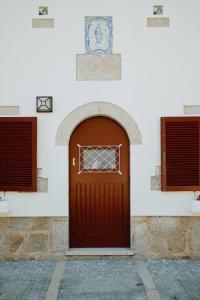 a brown door on a white building with two windows at Casa do Ave Riverside Suite in Vila do Conde +33 photos