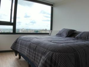 a bed in a room with a large window at Departamento 2D 2B 4-5 Personas in Temuco