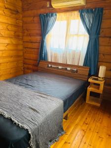 a bedroom with a bed and a window with blue curtains at ISE Family Cabin in Ise