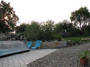 a patio with two blue chairs and a greenhouse at Penzion Helena a chata Helena in Střílky