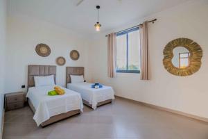 une chambre avec deux lits et un miroir au mur dans l'établissement Villa Tilila Mogador, à Essaouira 84 autres photos